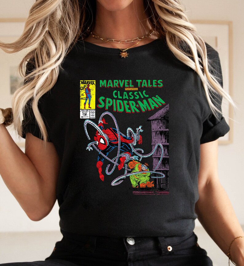 May include: Black t-shirt featuring a comic book cover design. The graphic includes the text "MARVEL TALES CLASSIC SPIDER-MAN" with an illustration of Spider-Man in action. The comic book cover art is in vibrant colors.
