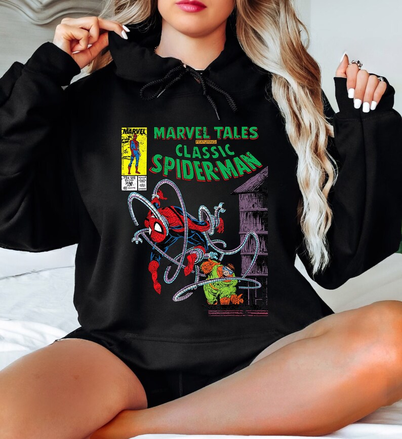May include: Black hoodie featuring a comic book graphic of Spider-Man. The graphic includes the text "Marvel Tales Classic Spider-Man" and a vintage comic book cover design. The hoodie is made of a soft material.