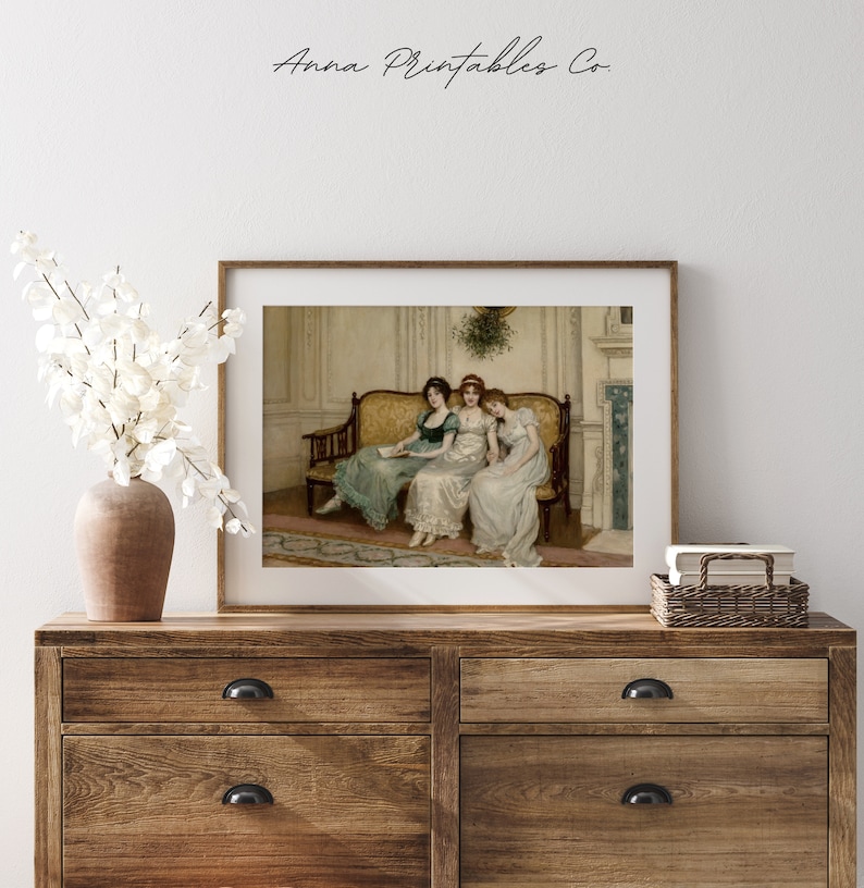 May include: A vintage painting of three women sitting on a yellow couch in a room with a fireplace. The women are wearing long dresses and are looking at a book. The painting is framed in a brown frame.
