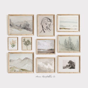 May include: A gallery wall featuring nine framed prints with various nature scenes, including landscapes, flowers, and trees. The frames are all made of light wood and have a simple, elegant design. The prints are all in muted tones of green, brown, and white, giving the gallery wall a calming and serene feel. The text "Anna Printables Co." is visible at the bottom of the image.