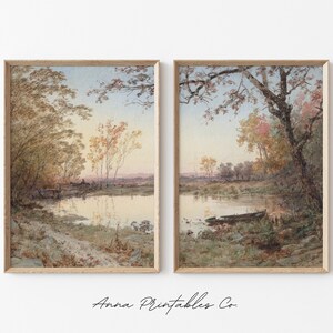 May include: A pair of framed watercolor paintings depicting a tranquil river scene with trees and a boat. The paintings are in a light wood frame and have a vintage aesthetic.