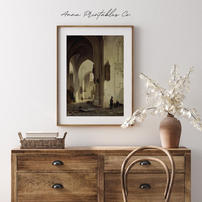 May include: A vintage painting of a church interior with high vaulted ceilings and stone pillars. The painting is in a light brown wooden frame and is hanging on a white wall.