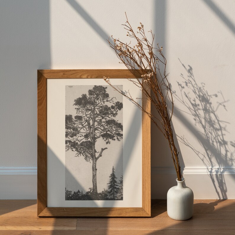 Peut inclure: Une estampe en noir et blanc encadr&eacute;e d'un arbre sur un fond simple. Le cadre est en bois et a une finition brun clair. Un arrangement de fleurs s&eacute;ch&eacute;es est au premier plan.