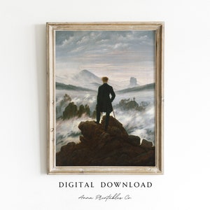 Könnte beinhalten: Digitaler Download eines gerahmten Landschaftsgemäldes. Das Kunstwerk zeigt eine Figur, die auf einem felsigen Gipfel steht und eine neblige Bergkette betrachtet. Das Gemälde befindet sich in einem rechteckigen, hellfarbigen Rahmen. Der Text "DIGITAL DOWNLOAD" und "Anna Printables Co." befinden sich unten.