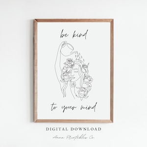May include: Black and white line art print of a woman with flowers in her hair. The text "be kind to your mind" is written below the image. The print is framed in a light wood frame.