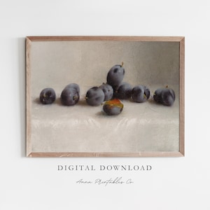Puede incluir: Una pintura enmarcada que representa una naturaleza muerta con un grupo de ciruelas de color morado oscuro sobre un mantel de lino blanco. Las ciruelas están dispuestas de forma casual y natural, con algunas superpuestas ligeramente. La pintura tiene un aspecto vintage y rústico, con un fondo texturizado que sugiere un lienzo envejecido.