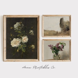 May include: Set of three framed vintage art prints featuring floral still life paintings. The first print shows a bouquet of white roses against a dark background. The second print shows a landscape scene with a figure walking in a field. The third print shows a bouquet of purple lilacs in a glass vase.