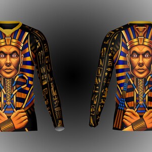 May include: Black long-sleeve shirt with a gold and blue pharaoh design. The pharaoh is wearing a gold crown and holding a staff. The shirt is covered in hieroglyphics.
