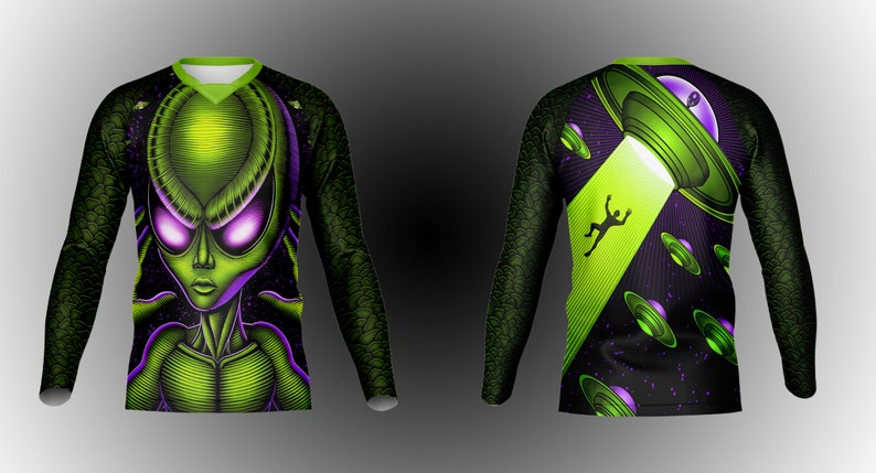 May include: A long-sleeved shirt with a green alien face on the front and a green UFO with a beam of light on the back. The shirt has a black background with purple and green accents.