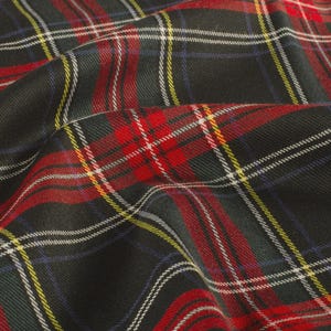 May include: A close-up shot of a folded fabric displaying a tartan pattern. The fabric is predominantly dark, with intersecting lines in red, white, yellow, and blue. The texture of the fabric is visible, creating a classic plaid design.