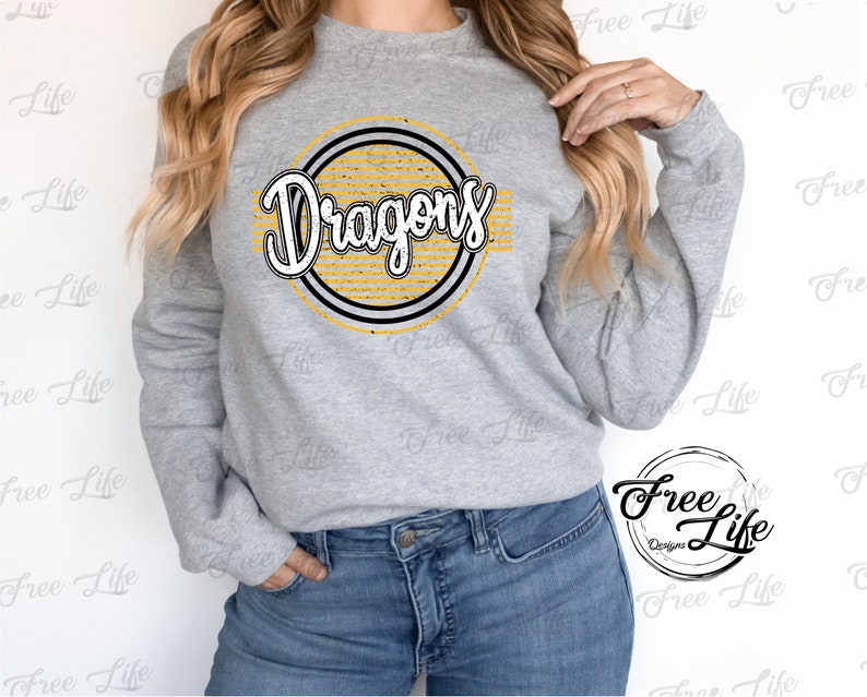 K&ouml;nnte beinhalten: Ein graues Sweatshirt mit einem gelben und schwarzen Kreisdesign, auf dem in einer Retro-Schrift "Dragons" steht.