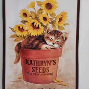 May include: A vintage-style metal sign featuring a brown tabby cat sleeping in a terracotta flower pot with a bouquet of yellow sunflowers. The pot has the text "Kathryn's Seeds They Grow Anywhere" printed on it. The sign also includes the text "Kathryn Watkins Proprietor Established 1939, Lincoln, Nebraska".