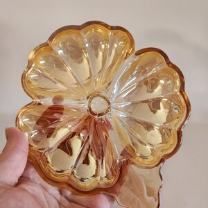 May include: A vintage amber glass dish shaped like a flower with a scalloped edge.