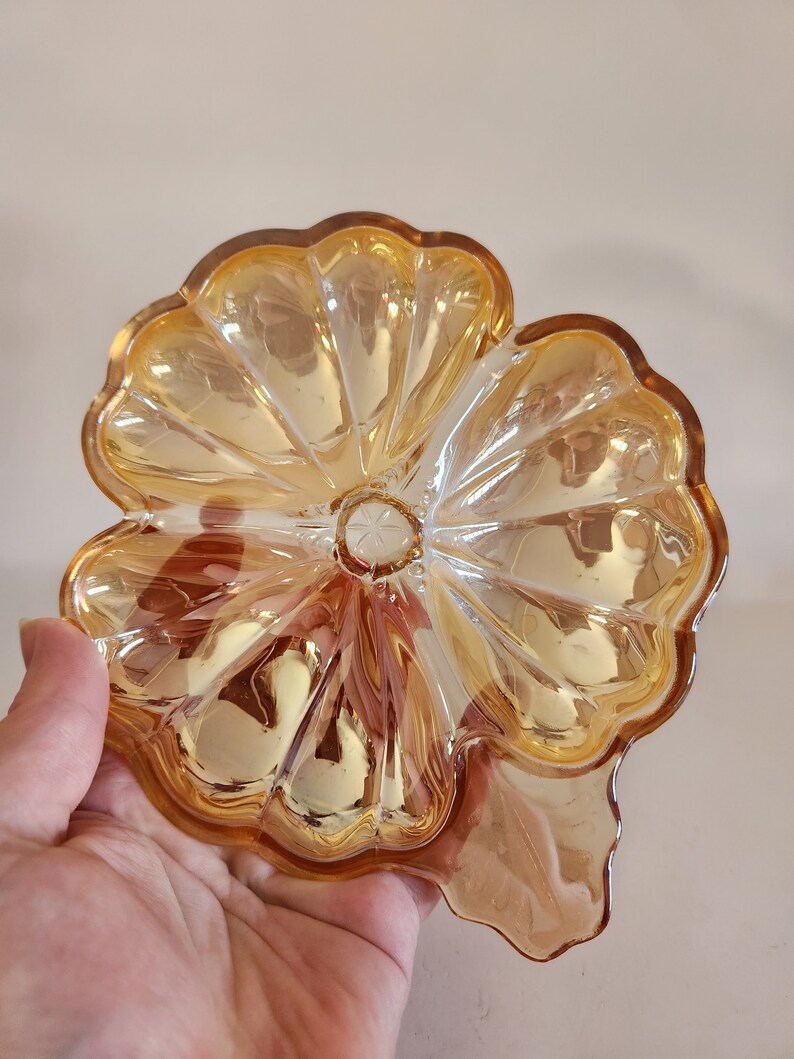 May include: A vintage amber glass dish shaped like a flower with a scalloped edge.