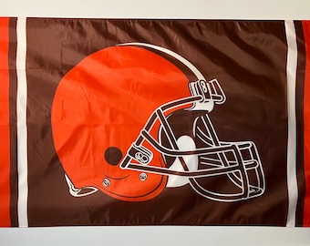 May include: A brown and orange football helmet flag with white stripes. The helmet is outlined in white and has a brown face mask.