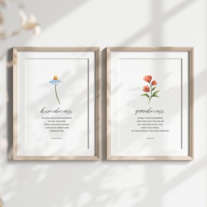 K&ouml;nnte beinhalten: Zwei gerahmte Drucke mit Aquarell-Blumenillustrationen und inspirierenden Zitaten. Der linke Druck zeigt eine blaue Blume mit dem Wort "kindness" und ein Zitat &uuml;ber Freundlichkeit und Mitgef&uuml;hl. Der rechte Druck zeigt eine rote Blume mit dem Wort "goodness" und ein Zitat &uuml;ber G&uuml;te und Liebe.