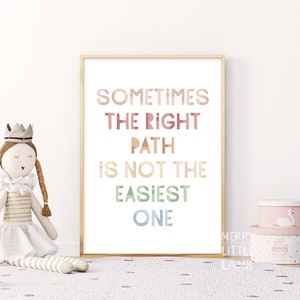 May include: A framed print with a white background and the text "Sometimes the right path is not the easiest one" in rainbow colors. The text is in a bold, sans-serif font.