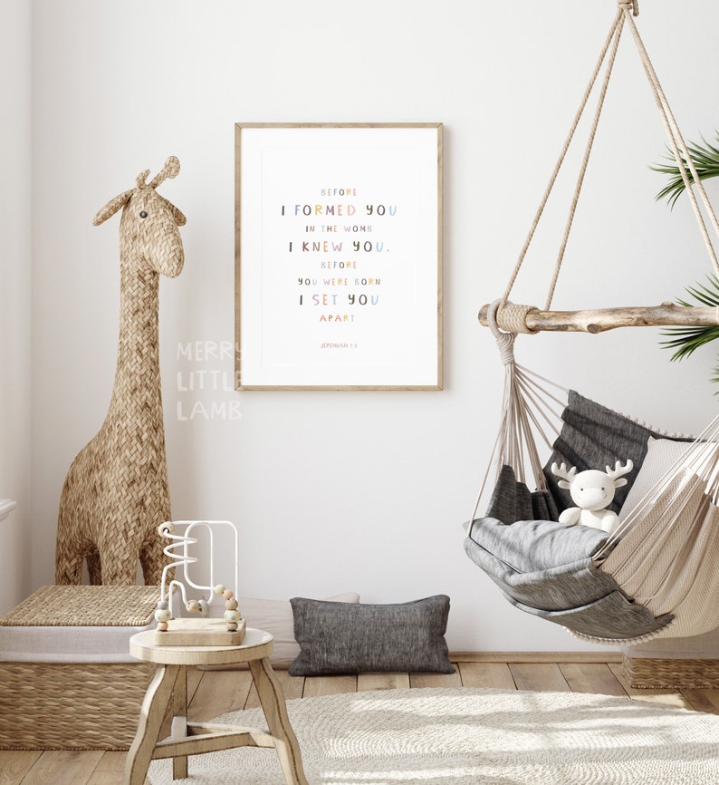 May include: A framed print with a white background and colorful text that reads "Before I formed you in the womb I knew you. Before you were born I set you apart. Jeremiah 1:5".