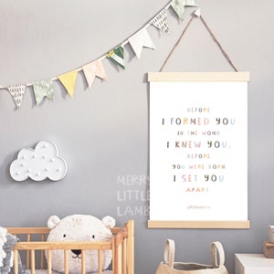 May include: A nursery print with a white background and colorful text that reads "Before I formed you in the womb I knew you. Before you were born I set you apart. Jeremiah 1:5".