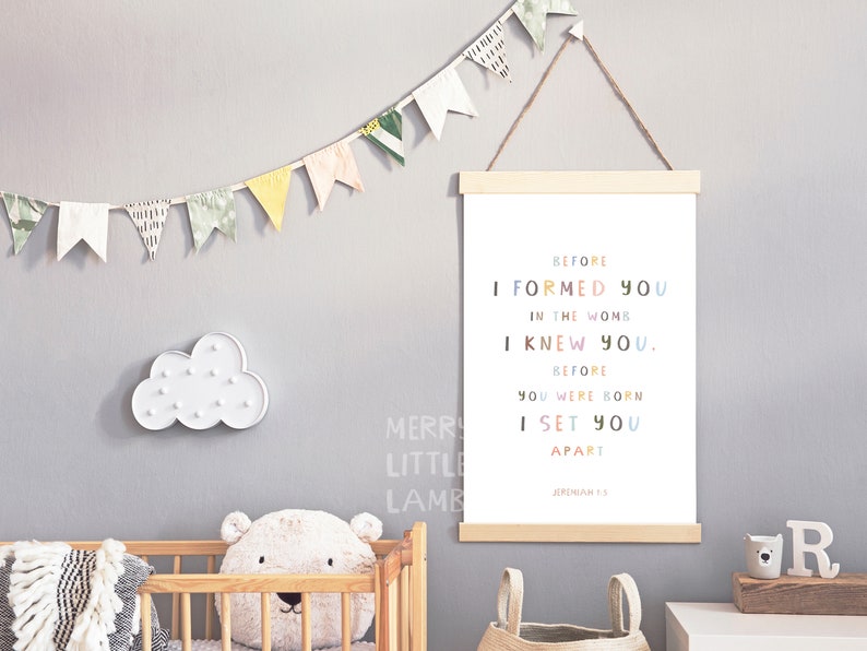 May include: A nursery print with a white background and colorful text that reads "Before I formed you in the womb I knew you. Before you were born I set you apart. Jeremiah 1:5".