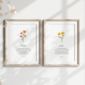 K&ouml;nnte beinhalten: Zwei gerahmte Drucke mit Aquarell-Blumenillustrationen und Bibelversen &uuml;ber Liebe und Freude. Der Druck auf der linken Seite zeigt einen Strau&szlig; orangefarbener Blumen mit dem Vers "Denn so sehr hat Gott die Welt geliebt, dass er seinen einzigen Sohn hingab, damit jeder, der an ihn glaubt, nicht verloren geht, sondern ewiges Leben hat." Der Druck auf der rechten Seite zeigt einen Strau&szlig; gelber Blumen mit dem Vers "Der Gott der Hoffnung erf&uuml;lle euch mit aller Freude und Frieden im Glauben, damit ihr durch die Kraft des Heiligen Geistes &uuml;berstr&ouml;mt werdet von Hoffnung."