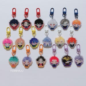 May include: A collection of eighteen acrylic charms featuring illustrated anime-style characters with diverse hair colours and outfits. Each charm is attached to a coloured plastic lobster clasp. The text noebyuu and hypmic charms is visible.