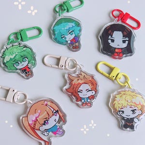 May include: Seven acrylic keyrings with anime-style character designs. Each keyring showcases a different character with distinct hair and clothing colours, attached to a metal clasp in various colours such as green, red, and yellow.
