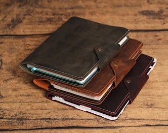 May include: Three leather-bound journals stacked on top of each other. The top journal is dark green, the middle journal is brown, and the bottom journal is dark brown.