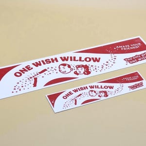 May include: Two rectangular white stickers with red graphic designs. The text reads ONE WISH WILLOW, AMAZE YOUR FRIENDS!, and You only get ONE WISH. The graphics include two faces, a cracking stick, and stars, all rendered in a bold red ink.