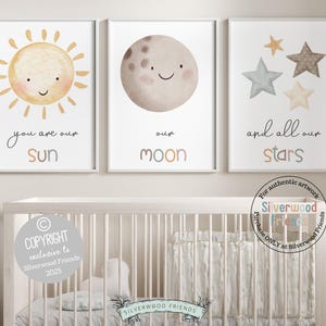 Pode incluir: Três impressões de aquarela com um sol, uma lua e estrelas. O sol tem um rosto feliz e o texto "você é nosso sol". A lua tem um rosto feliz e o texto "nossa lua". As estrelas têm o texto "e todas as nossas estrelas".