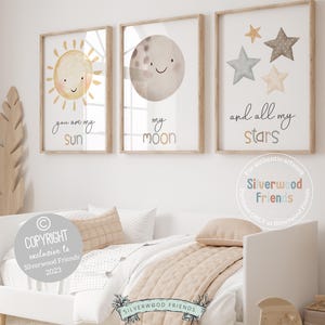May include: Three watercolor prints with a sun, moon, and stars. The sun is yellow with a smiling face and the text "you are my sun". The moon is gray with a smiling face and the text "my moon". The stars are various colors with the text "and all my stars".