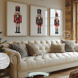 May include: Three framed prints of nutcracker soldiers in red, black, and gold uniforms hang above a cream-colored tufted sofa with plaid and patterned pillows. A Christmas tree is on the left.