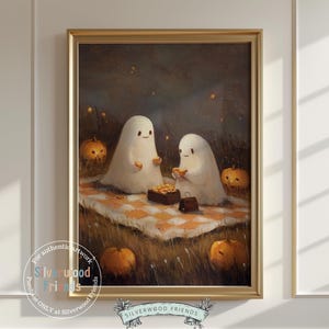 Puede incluir: Una obra de arte enmarcada representa a dos fantasmas blancos amistosos disfrutando de un picnic sobre una manta a cuadros. La escena está ambientada en un campo con calabazas y un fondo oscuro. La obra está en un marco dorado.