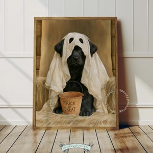 Pode incluir: Um cão preto vestindo um traje de fantasma branco feito de um lençol com buracos para os olhos. O cão está sentado numa superfície bege texturizada e segura um pequeno balde laranja com o texto Trick or Treat impresso em letras pretas.