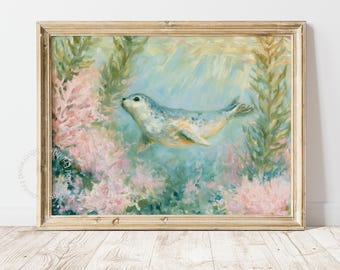 May include: An oil painting in a light wood frame depicting a spotted seal swimming underwater. The scene features soft brushstrokes of blue and green water, surrounded by textured pink coral and tall green seaweed, creating a serene aquatic environment.