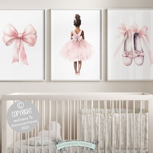 May include: Three watercolor prints featuring a ballerina in a pink tutu, a pink bow, and a pair of pink ballet shoes. The prints are framed in white and are displayed on a white wall above a white crib.