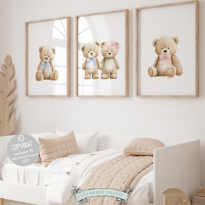 Puede incluir: Tres impresiones enmarcadas con ilustraciones de osos de peluche en acuarela. Cada oso tiene un lazo, uno azul, uno rosa y otro con un lazo rosa. Las impresiones se muestran sobre una cama blanca con ropa de cama de tonos neutros.