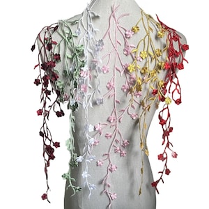 May include: Assortment of five floral embroidery trims in different colours, including red, green, white, pink, and yellow. Each trim features a delicate vine design with small flowers.
