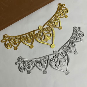 Peut inclure: Deux ornements métalliques décoratifs et ornés. L'un est doré et l'autre argenté. Les deux ont un design similaire avec des volutes et des boucles complexes.