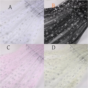 May include: Four samples of sheer fabric with silver snowflake patterns. The fabric is white, black, pink, and cream.