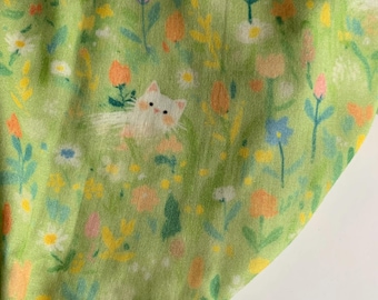 Könnte beinhalten: Ein hellgrüner Stoff mit einem sich wiederholenden Muster aus weißen Katzen, Blumen und Blättern in Rosa-, Gelb- und Orangetönen. Das Design hat eine skurrile, frühlingshafte Ausstrahlung.