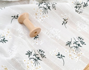 Op de afbeelding: Witte stof met een delicaat bloemenpatroon in tinten wit en groen. De stof heeft een subtiele textuur en is perfect voor knutselprojecten.