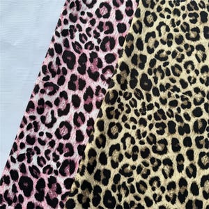 May include: Two fabric samples with leopard print patterns are displayed. One has a pink and black design, the other a tan and black pattern. These fabrics are suitable for clothing or home decor projects.