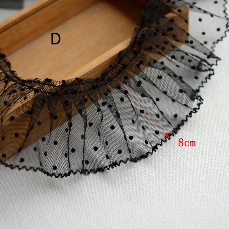May include: Black polka dot mesh trim with a ruffled edge. The trim is 8 inches long.