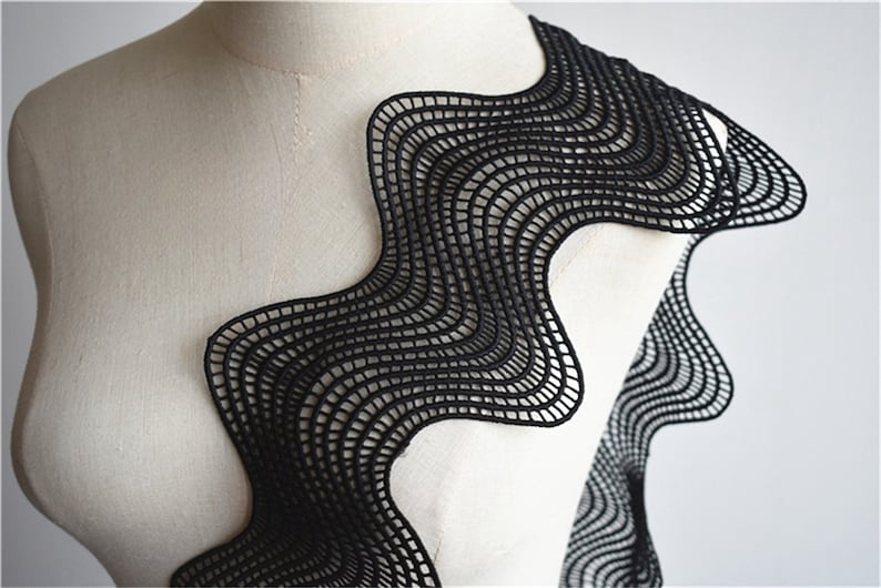 May include: Black wavy lace trim with a geometric pattern. The lace is delicate and intricate, with a scalloped edge.