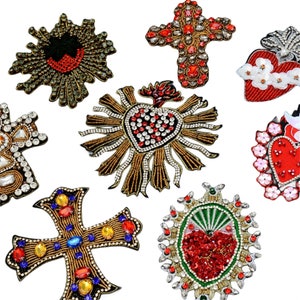 Può includere: Assortimento di otto toppe ricamate da stirare con immagini religiose. Le toppe sono decorate con strass, paillettes e perline in tonalità di rosso, oro e bianco. I disegni includono una croce, un cuore e un cuore sacro.