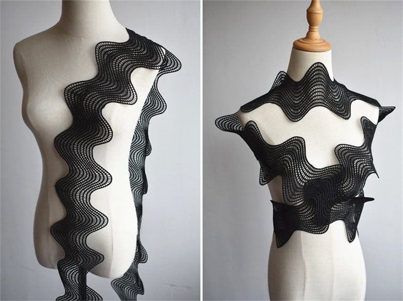 May include: Black wavy lace trim with a scalloped edge. The lace is shown on a white mannequin form.