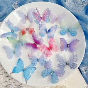 May include: Assortment of 14 colorful butterfly-shaped embellishments made of sheer fabric with a rhinestone accent in the center of each butterfly.