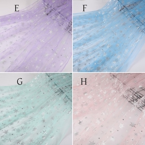 May include: Four swatches of sheer fabric with silver snowflake patterns. The swatches are in purple, light blue, light green, and pink.