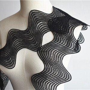 May include: Black lace fabric with a wavy, abstract design. The fabric is delicate and intricate, with a fine mesh pattern.